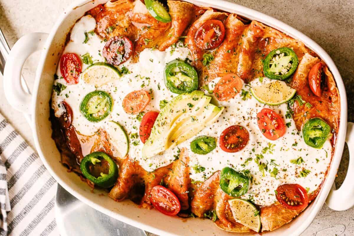Baked chicken enchiladas with red sauce in a casserole dish.