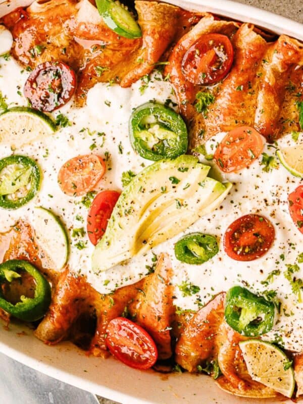 Baked chicken enchiladas with red sauce in a casserole dish.