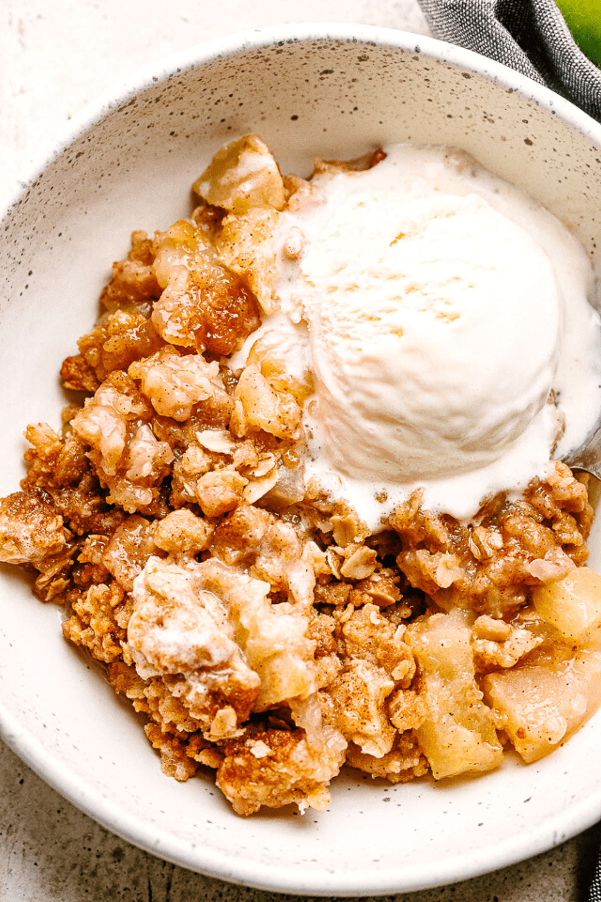 Apple Crumble served in a bowl with vanilla ice cream.