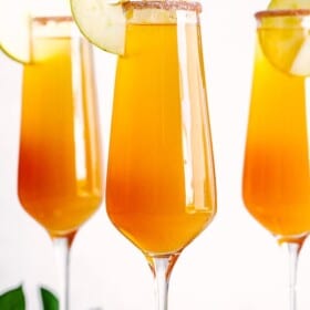 Apple Cider Mimosa in champagne flutes with apple slices.