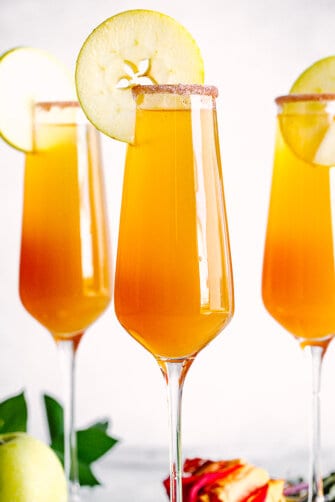 Apple Cider Mimosa in champagne flutes with apple slices.