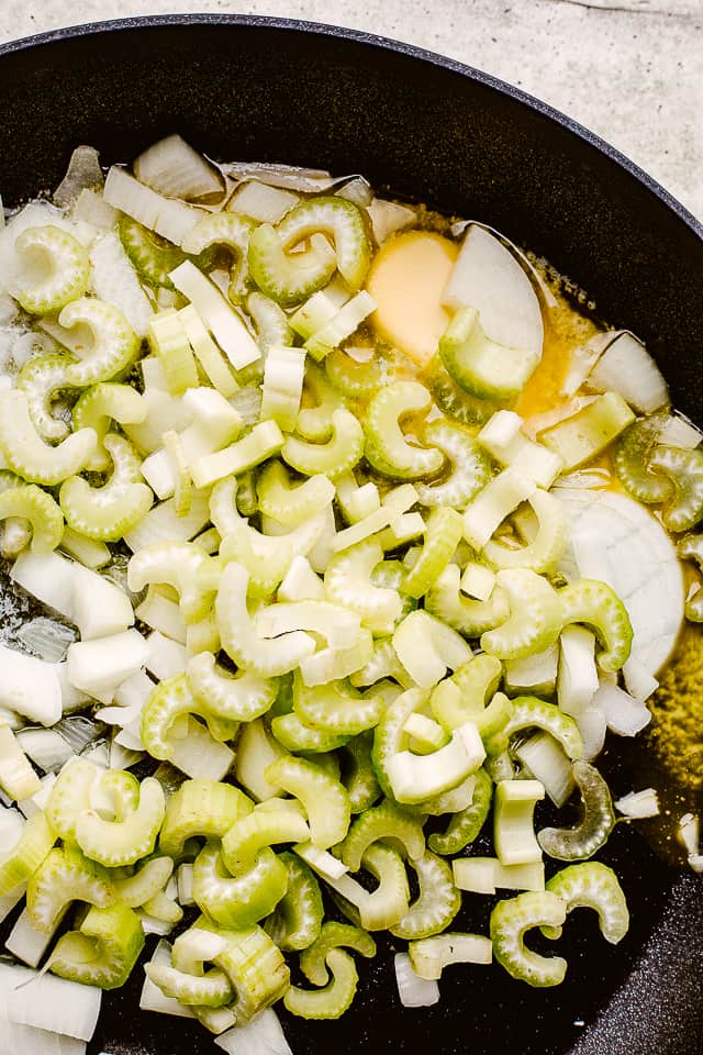 Cooking onions and celery in butter in a skillet.