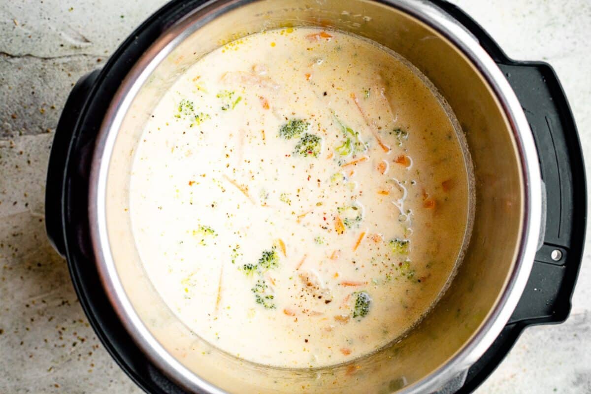 Creamy broccoli cheese soup with shredded chicken and carrots in an Instant Pot insert.
