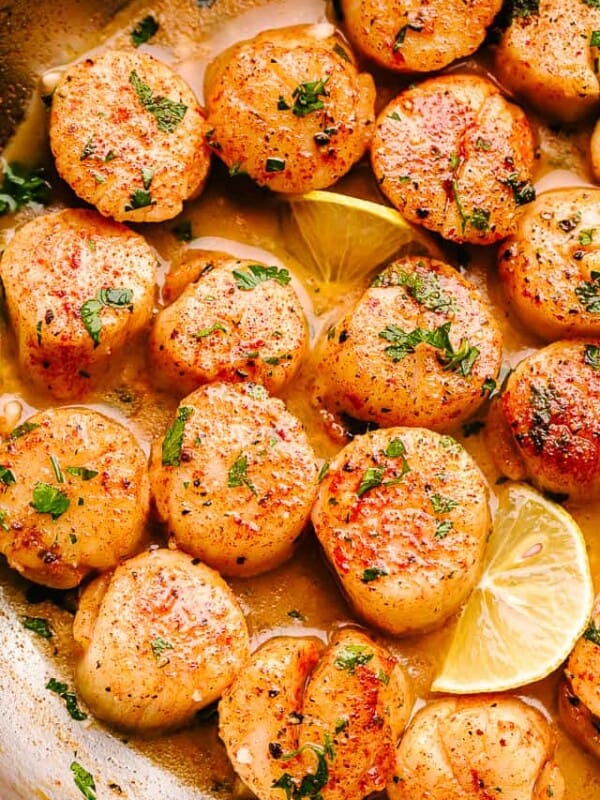 scallops in butter sauce with parsley and lemon slices