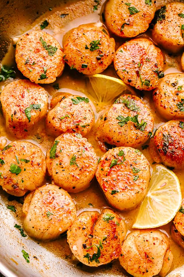 scallops in butter sauce with parsley and lemon slices