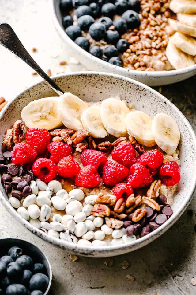 homemade oatmeal topped with berries, bananas, nuts, and raisins