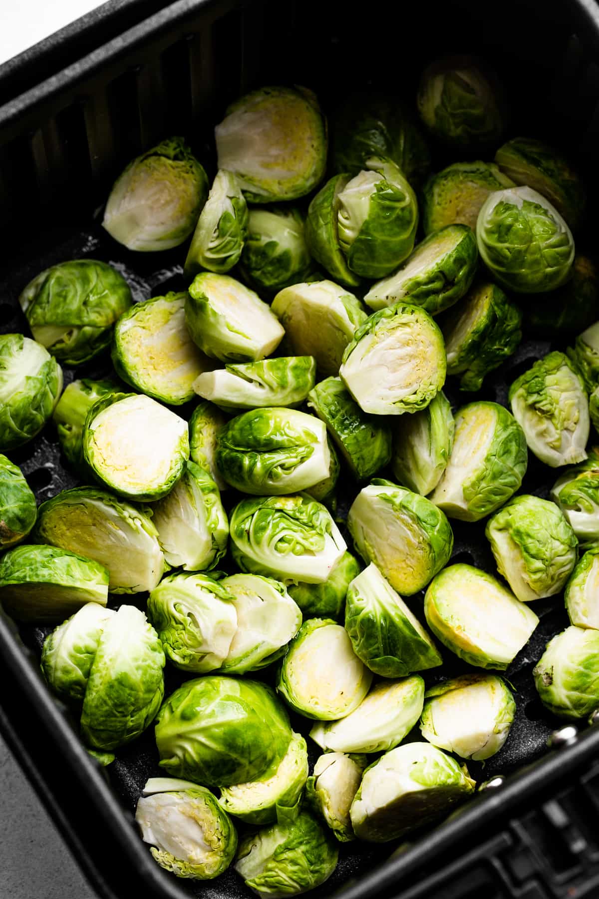 Raw brussel sprouts in an air fryer basket