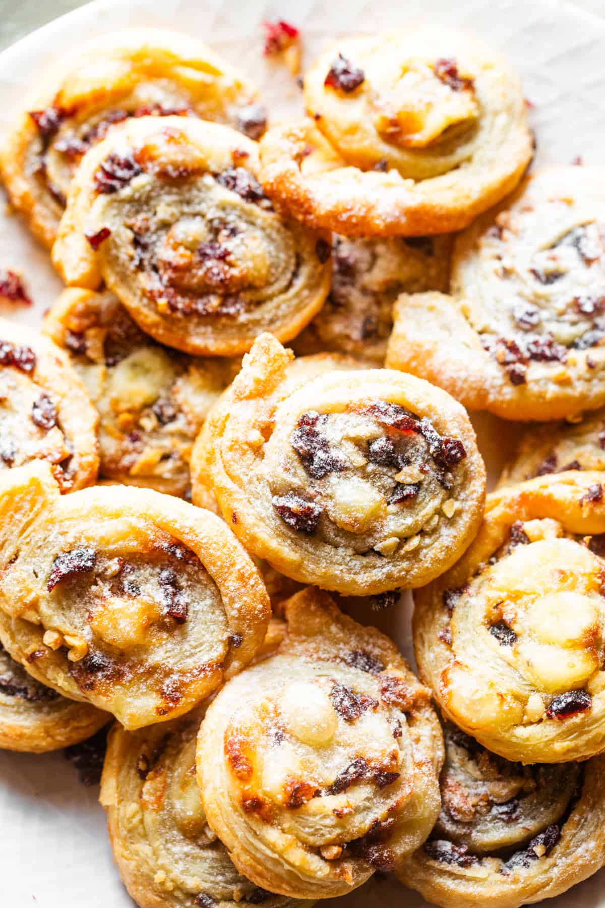 Puff pastry pinwheels arranged on a serving plate and are dusted with powdered sugar.