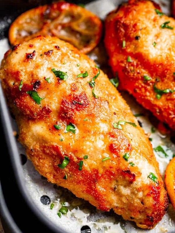 Two crispy fried chicken breasts in an air fryer basket.