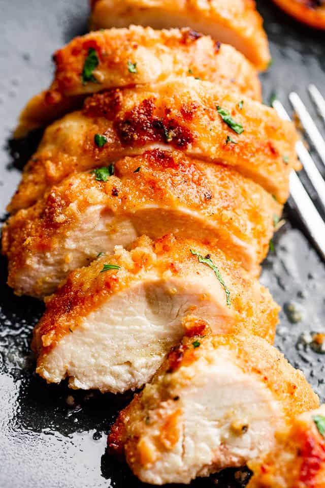 A fried boneless skinless chicken breast, sliced and sprinkled with herbs.