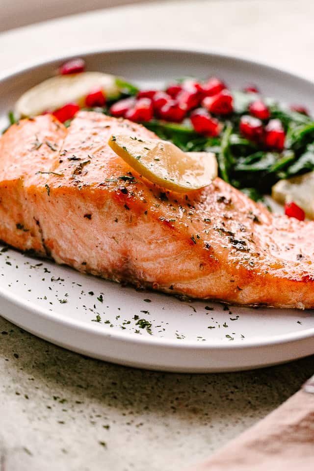 cooked salmon fillet on a playr with spinach and tomatoes.