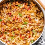 Frying sliced cabbage and bacon in a skillet.