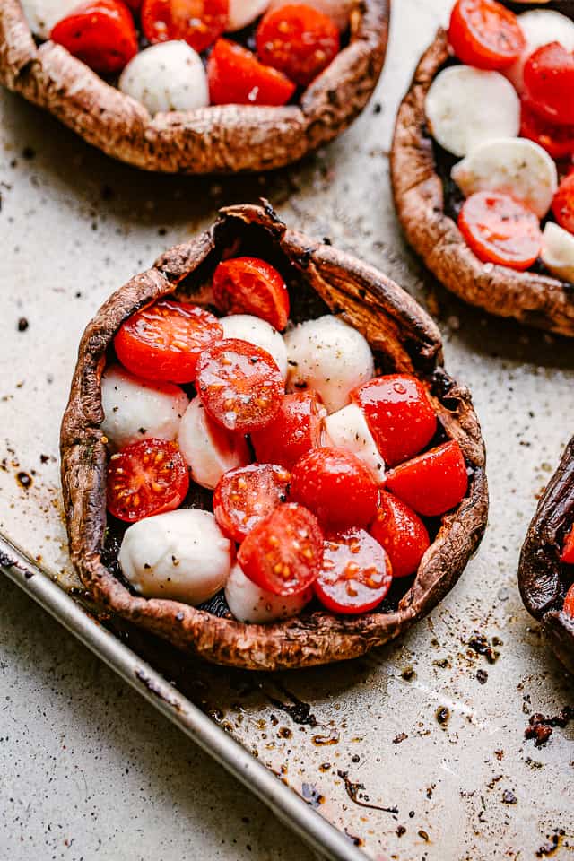 Mushroom caps stuffed with cherry tomatoes and mozzarella cheese balls.