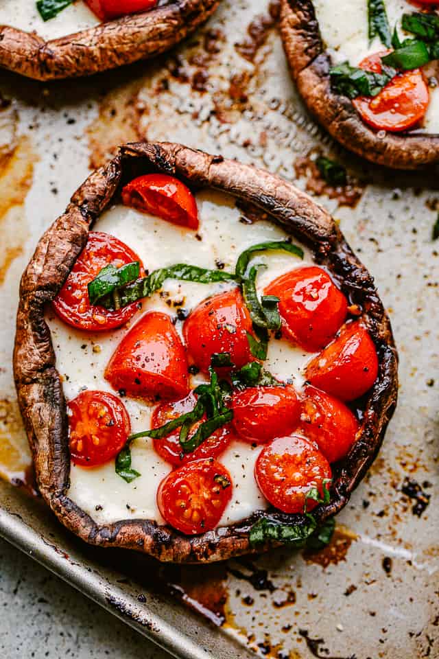 Caprese stuffed mushrooms arranged on a baking sheet.