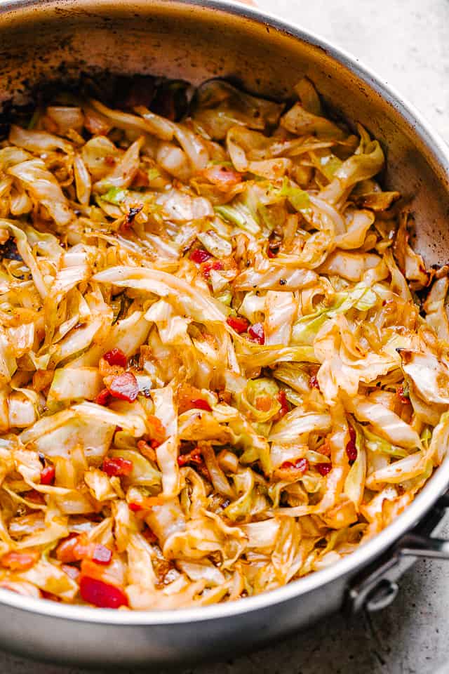 A skillet with cooked cabbage and bacon.