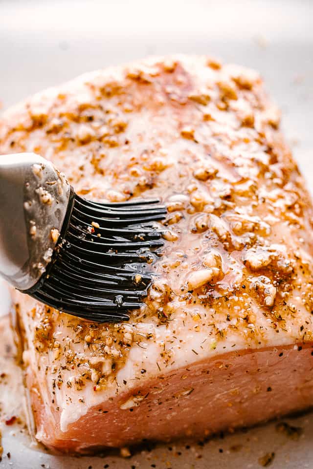 Brushing pork loin with garlic balsamic mixture.