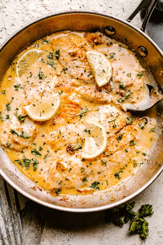 tilapia in lemon cream sauce pictured in a skillet
