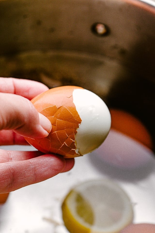 Hand holding a hard boiled egg being peeled