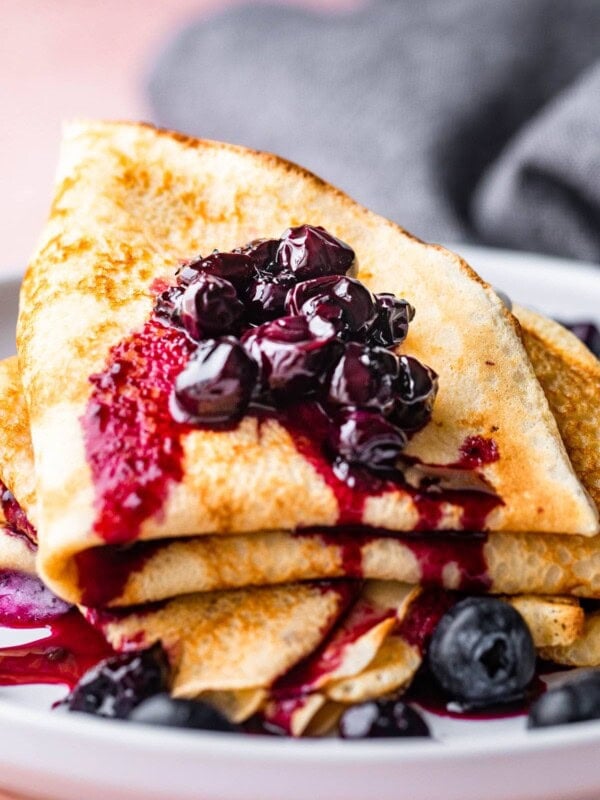 A stack of crepes topped with a homemade blueberry sauce.