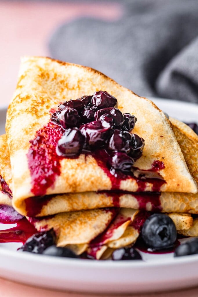 A stack of crepes topped with a homemade blueberry sauce.