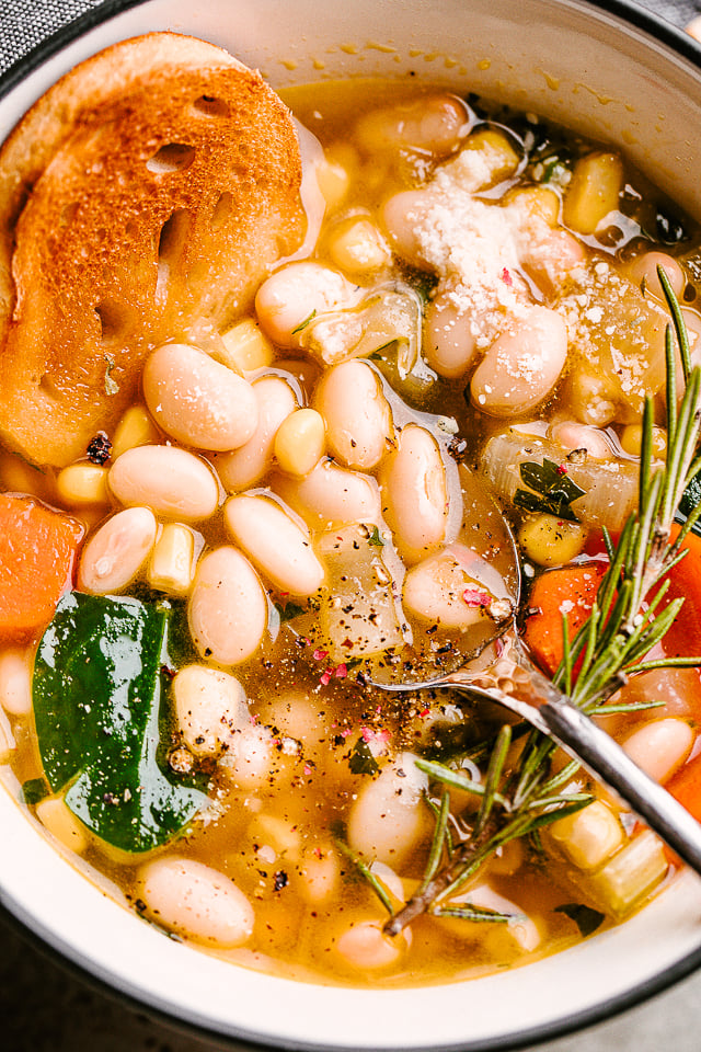 Close-up image of bean soup served in a bowl with a spoon resting in the soup. 