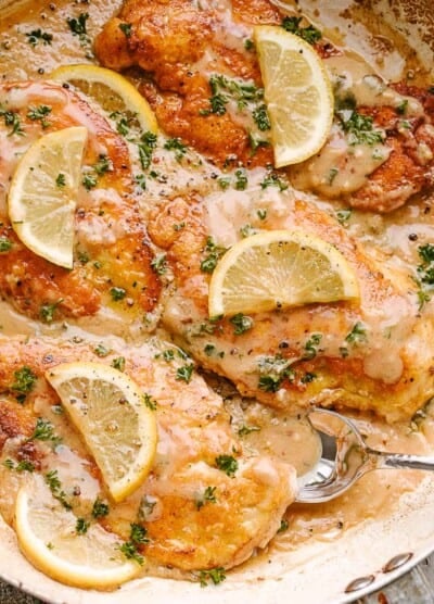 Sauce spooned over chicken francaise served with lemon and fresh herbs