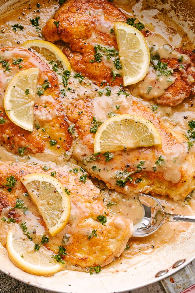 Sauce spooned over chicken served with lemon and fresh herbs