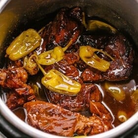 A pot roast cooking in an Instant Pot with pepperoncini