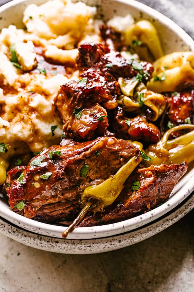 Cut-up Mississippi pot roast served over mashed potatoes with pepperoncini.