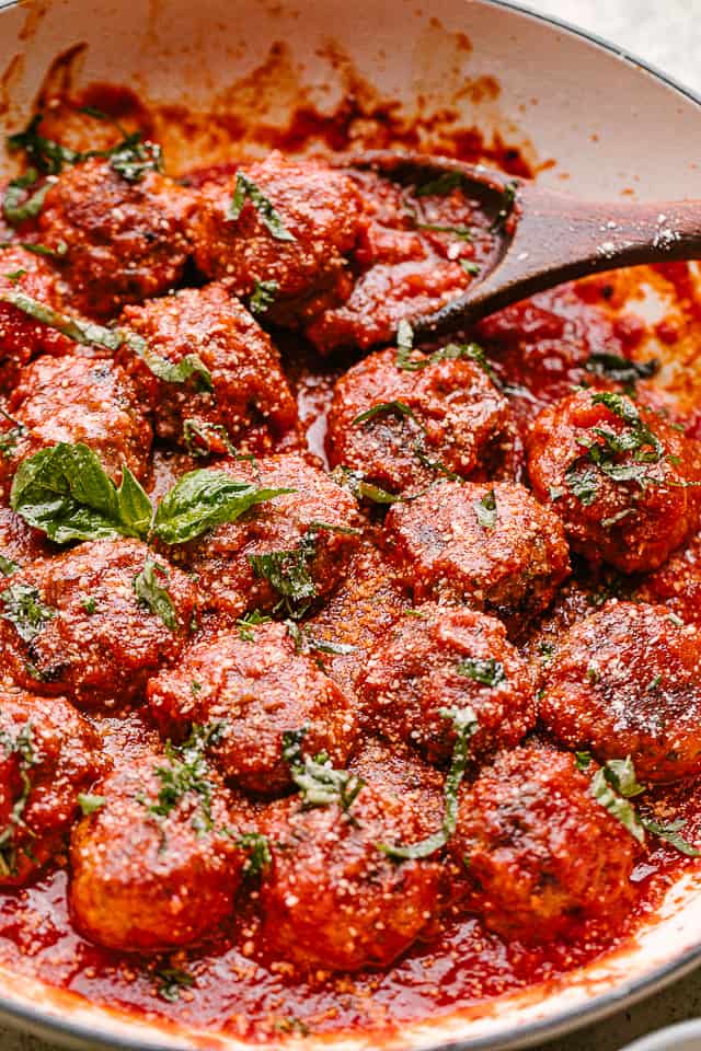 baked meatballs in a pan with marinara and topped with basil. Ready to be served.