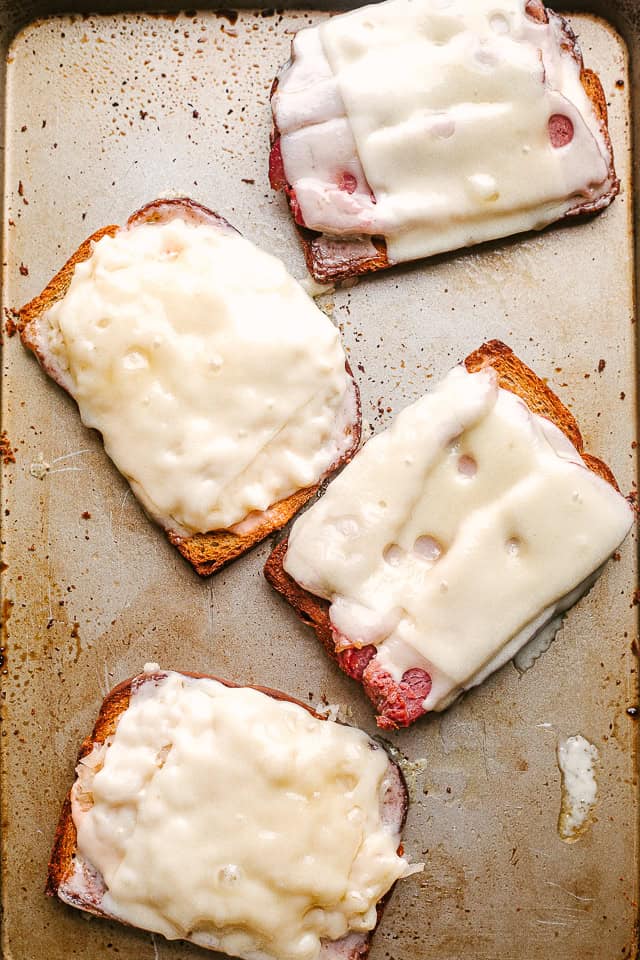 Four slices of bread topped with cheese and sauerkraut.