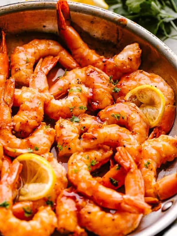 Skillet barbecue shrimp in a pan garnished with lemon wedges and parsley
