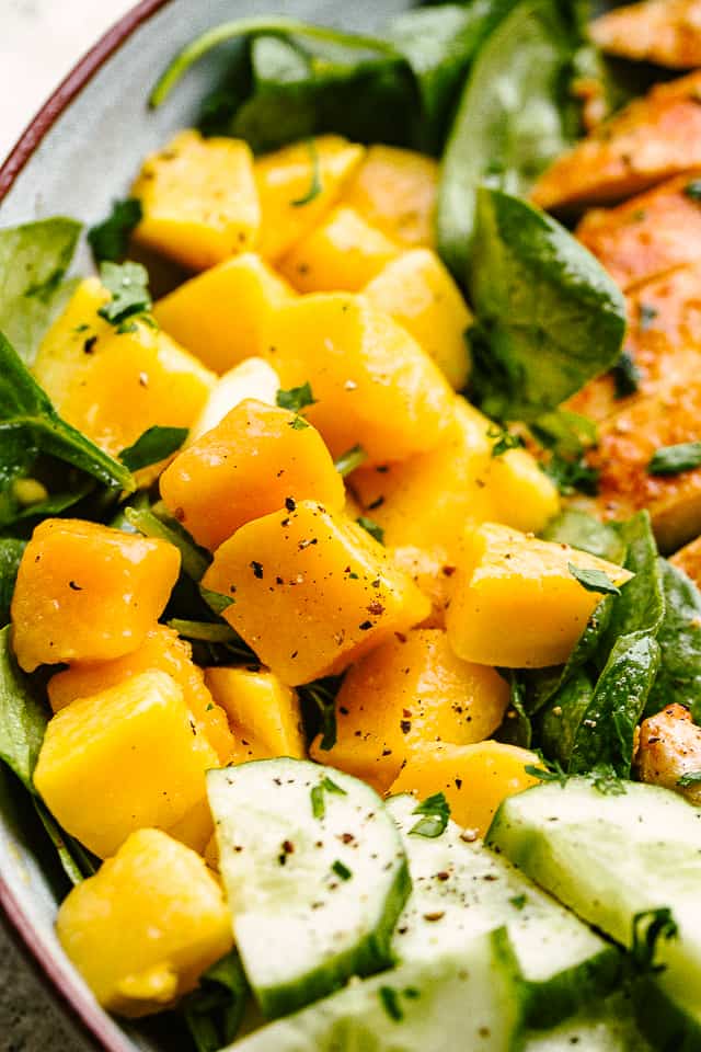 diced mangoes on top of lettuce leaves