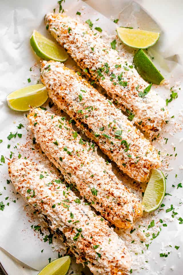 Elote (Mexican Street Corn) served on a platter with lime wedges.
