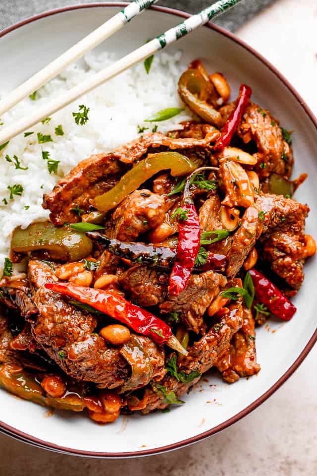 Kung Pao beef with white rice served on a plate with chopsticks. 