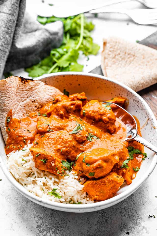 Homemade chicken tikka masala in a bowl with rice and naan