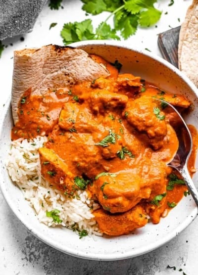 A bowl of chicken tikka masala with rice and naan