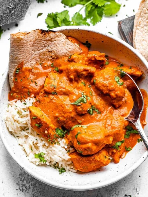 A bowl of chicken tikka masala with rice and naan