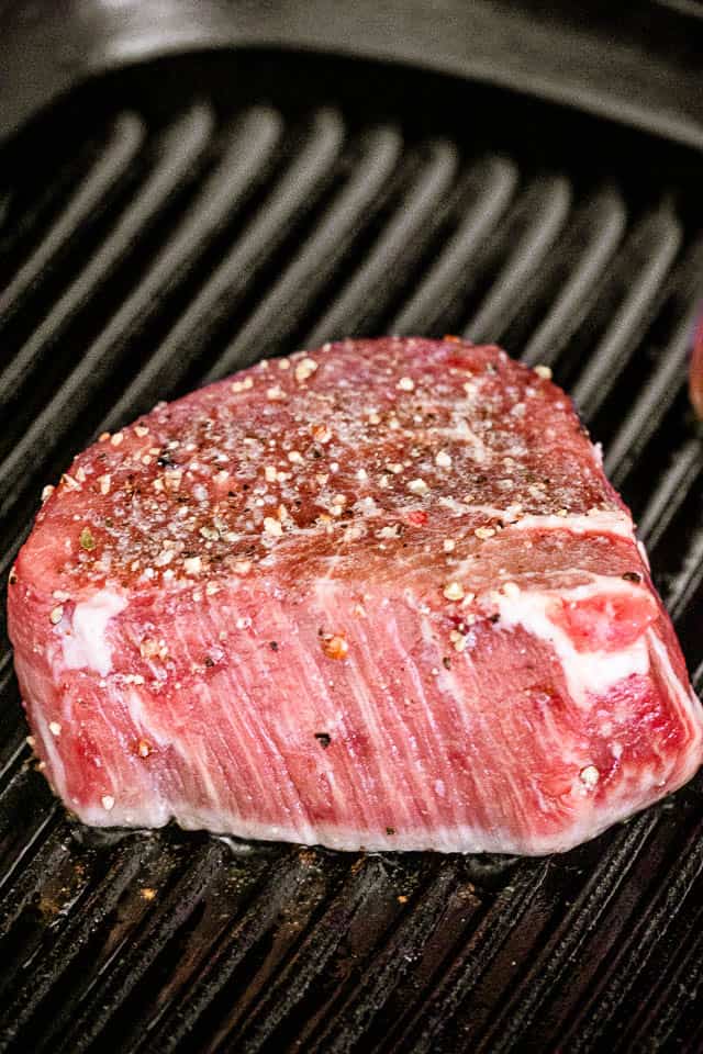 Raw steak on a grill ready to be cooked