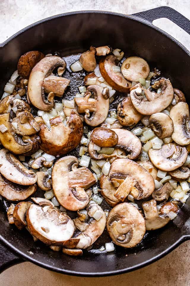 frying sliced mushrooms and onions in a cast iron skillet