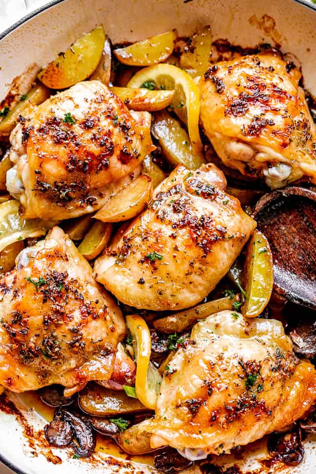 baked chicken thighs in a pan with potatoes and lemon slices