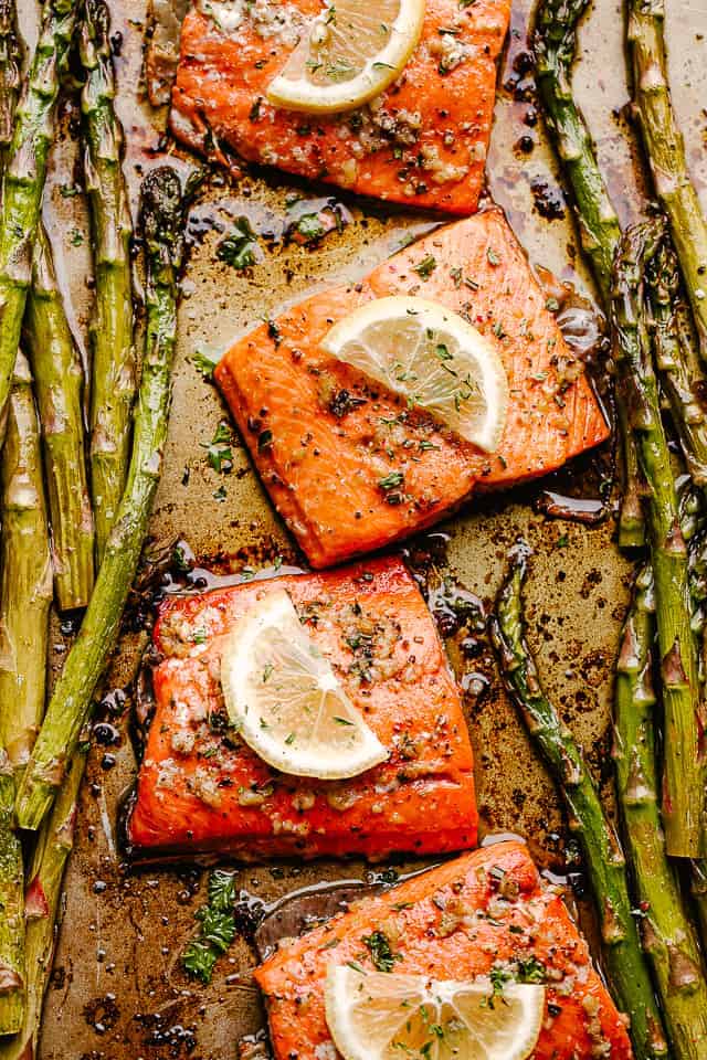 baked salmon fillets topped with lemon slices and asparagus spears on either side