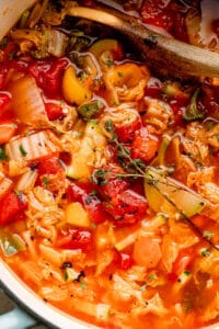 close up view of mixing cabbage soup with wooden spoon