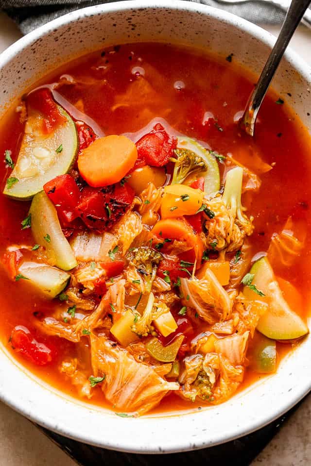 This easy cabbage soup recipe is packed with tender veggies simmered in a flavorful tomato broth. It’s hearty, delicious, and ready in 30 minutes! Bowl of cabbage soup with tender cabbage, zucchini, carrots, broccoli, bell peppers, and tomatoes.
