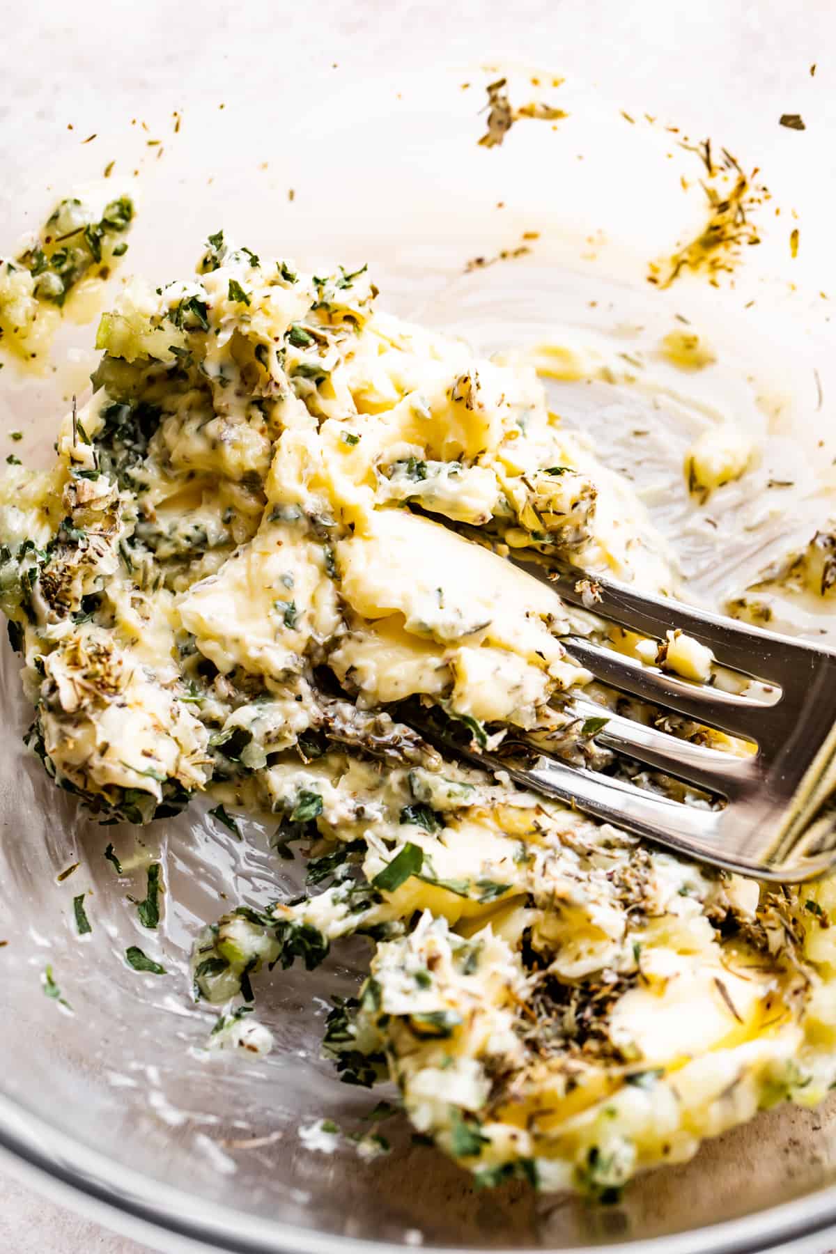 using a fork and mashing a garlic herb compound butter