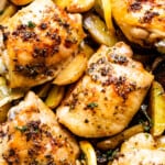 up close photo of garlic butter baked chicken thighs atop potatoes and mushrooms