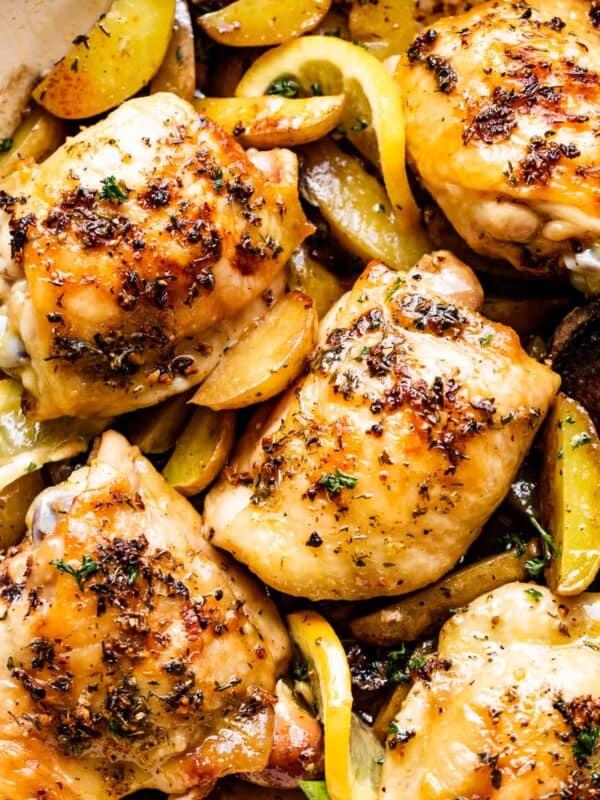 up close photo of garlic butter baked chicken thighs atop potatoes and mushrooms