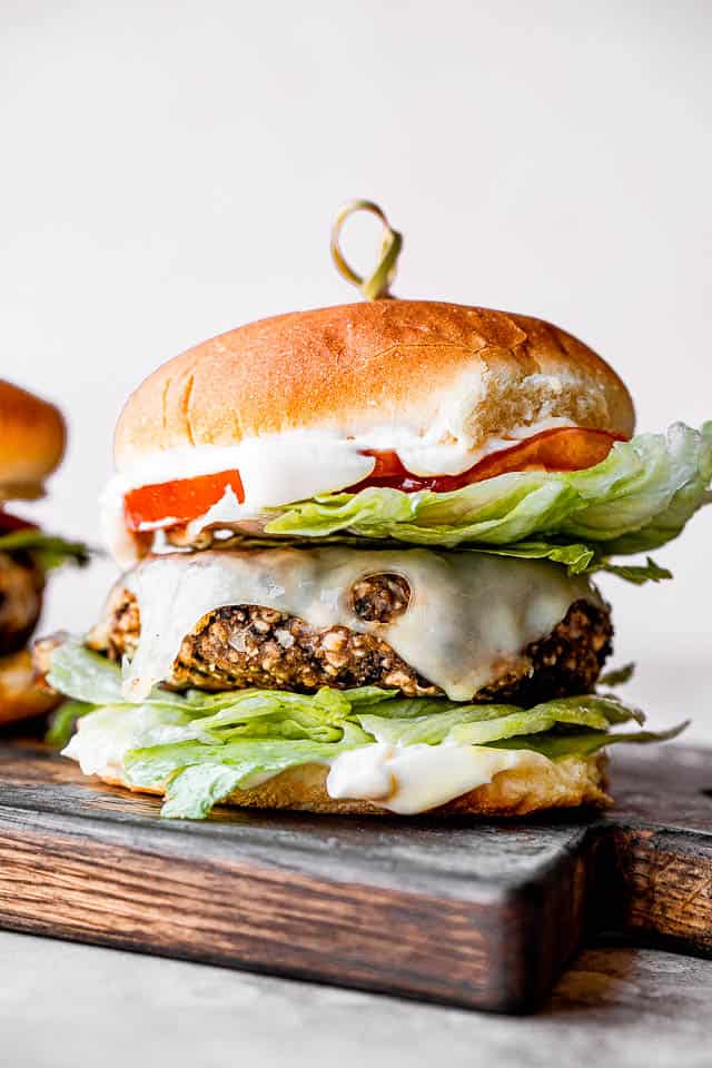 black bean burger set on a wooden chopping board with a toothpick inserted through the center of the burger