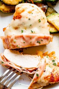 top view close up shot of a fork set through a slice of grilled cordon bleu chicken