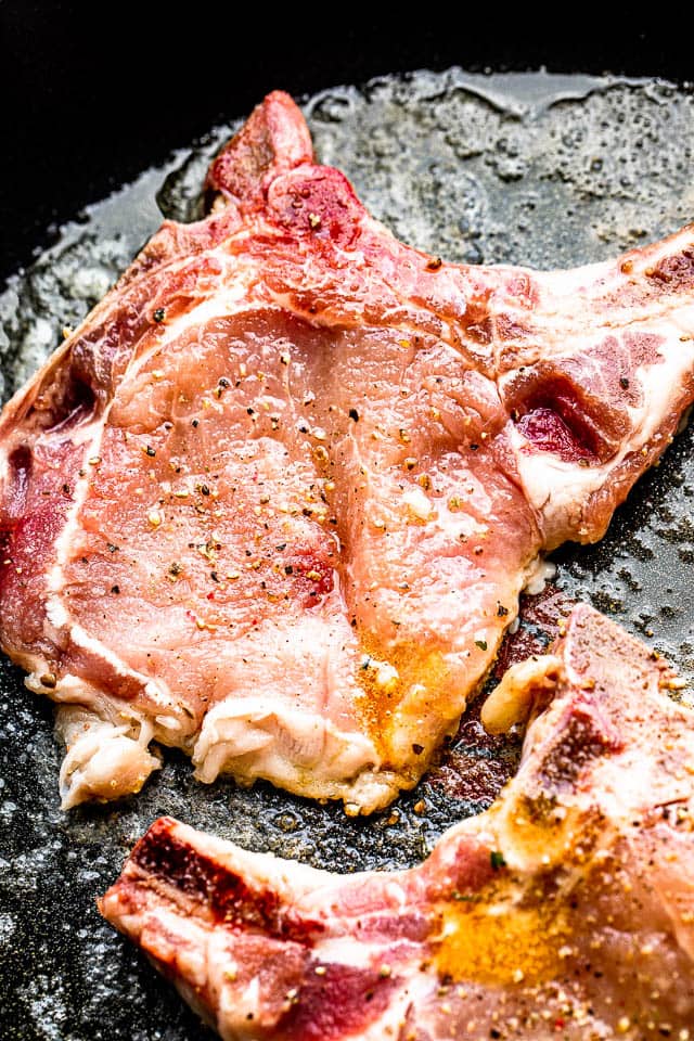 seasoned raw pork chops on a dark background